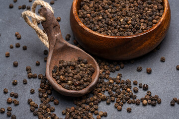Black peppercorns on black stone table  background