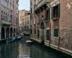 Naklejka premium Venetian canal with rustic buildings and boats.