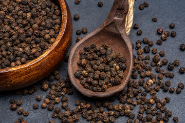 Black peppercorns on black stone table  background