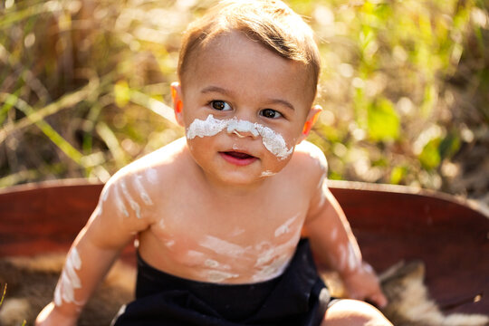 Happy little Aboriginal toddler boy sitting in coolamon in Australian bushland