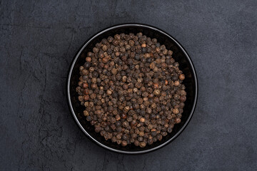 Black peppercorns on black stone table  background