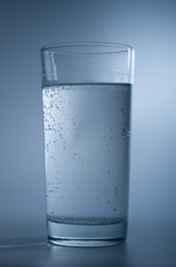Glass with soda water on blue background