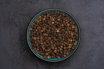 Black peppercorns on black stone table  background