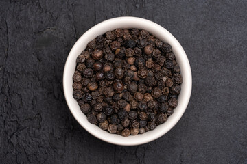 Black peppercorns on black stone table  background