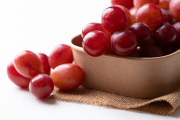 Fresh red grapes in paper bowl on white background, Healthy fruit
