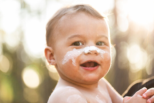Smiling happy portrait of young Aboriginal toddler boy in ochre paint outdoors