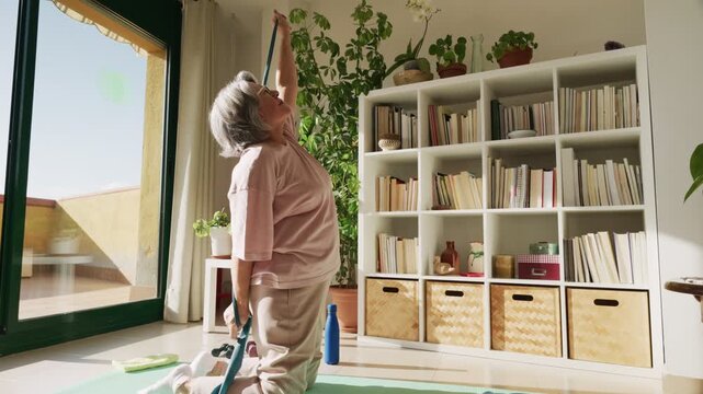 Senior woman stretching with yoga strap at home
