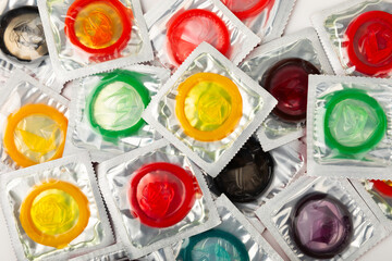 Condoms isolated on white background. Colorful fruit-colored condoms in packaging. Safe sex concept. Contraceptive. Different birth control methods. Aids prevention. World AIDS Day. Sexual health.