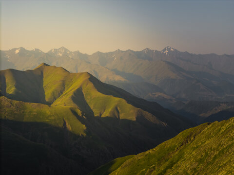 Aerial view of sunlight kissing the jagged peaks of the Alazani pass, painting the landscape in hues of emerald and gold, Chala, Kakheti, Georgia.