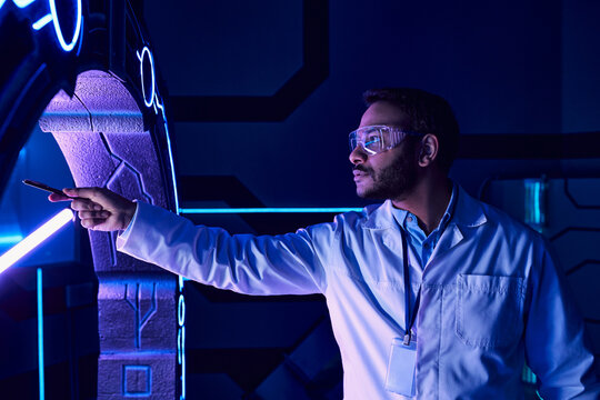 Scientist examines alien technology in futuristic lab setting at night - Powered by Adobe