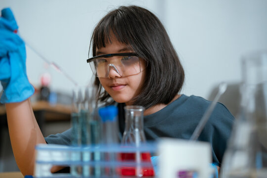 Young girl conducting a science experiment in a laboratory setting during the day