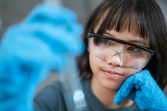 Young girl conducting a science experiment in a laboratory setting during the day