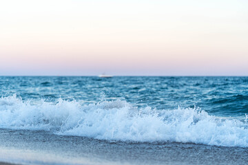Calm Beach Waves with Blured Boat on Horizon at Dusk