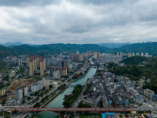 Xuan'en County China shows a city nestled among green hills with a river flowing through it and buildings reaching towards the sky.