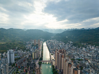 Xuan'en County, Hubei Province, China, city nestled beside a winding river, with buildings reaching towards the sky and green mountains framing the view.