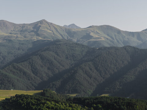 Aerial view of the Caucasus Mountains, where verdant forests meet rugged peaks under a soft, hazy sky, Upper Omalo, Kakheti, georgia.