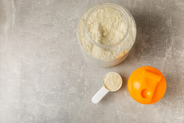 Fototapeta premium Protein shake with protein powder on a colored background. The powder is mixed with water or milk. A dietary supplement for a balanced diet. Whey protein. Fitness and gym diet nutrition.