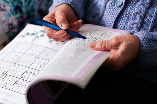 Senior person doing sudoku puzzle in book