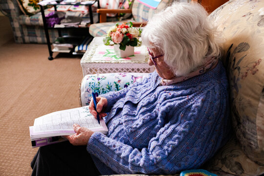 Senior person doing sudoku puzzle in loungeroom at home