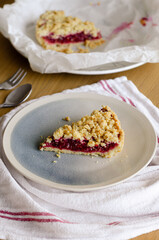Close up of Italian sbriciolata crumble pie slice with organic plum jam on plate over white towel