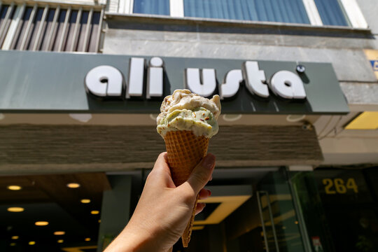 Istanbul, Turkey - July 2, 2019: Hand holding ice cream cone in front of Ali Usta ice cream shop in the Kadikoy district on the Asian side of Istanbul with bright sunny day atmosphere