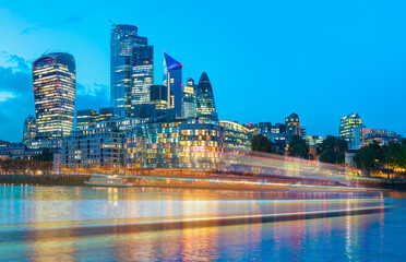 Obraz premium Modern skyline on Thames river at twilight blue hour - London, United Kingdom - Motion speed light of passing ferry