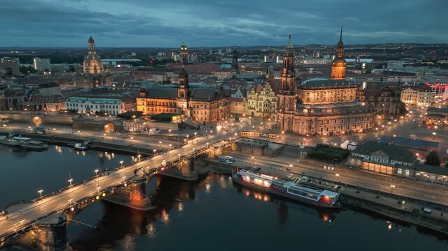 Cityscape of Dresden illuminated by evening lights along the Elbe River with historic architecture. Aerial evening shot of Dresden, Germany