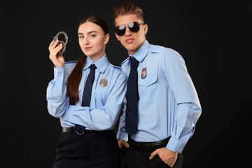 Young policewoman and policeman on black background