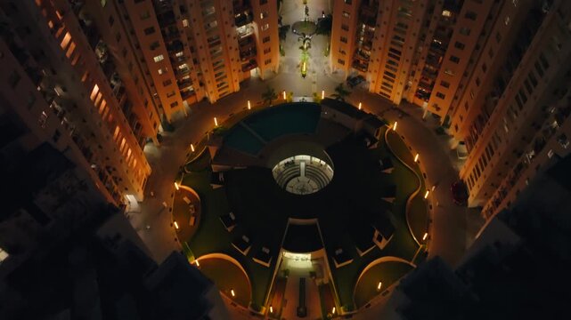 Aerial view of the illuminated Orris Aster Court, showcasing the building's lit facade contrasting against the dark night, Gurugram, Haryana, India.