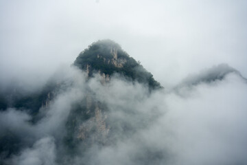 Misty mountains rise in China's Yichang region, their peaks shrouded in clouds and mist.