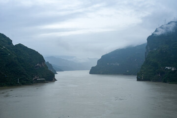 The Yichang Three Gorges in China presents vast river waters flowing between steep, green mountains...