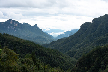Majestic mountains rise in Yichang City, China, with a bridge spanning a distant valley under a...