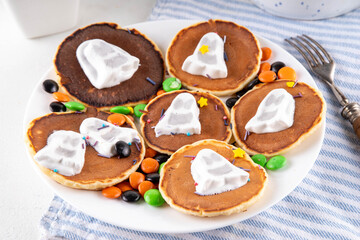 Tasty Halloween pancakes topped with marshmallow ghosts. Halloween morning dessert, for breakfast or brunch, with colorful candies, sweets and Halloween decorations