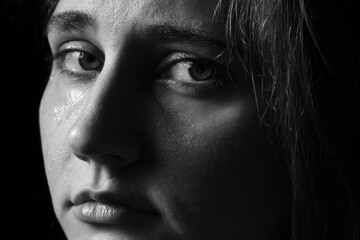 Fototapeta premium Sad woman crying on dark background, closeup. Black and white effect