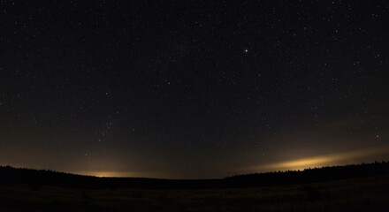 Fototapeta premium Night sky full of stars above dark land and faint light on the horizon