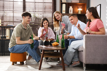 Group of friends playing cards at wooden table indoors