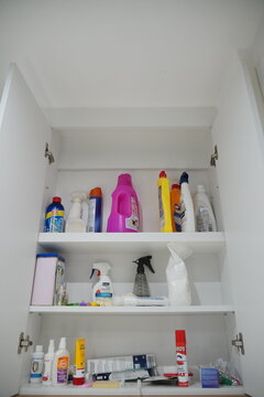 Inside view of a disorganized home storage cabinet packed with numerous cleaning products and supplies from various brands