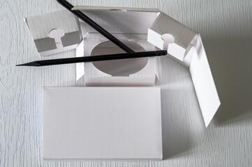 Still life with pencils and white folded cardboard on a white background.