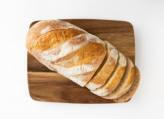 Bread loaf sliced on wooden board top view on white background.
