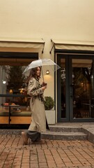 Obraz premium Girl in trench coat walking with umbrella