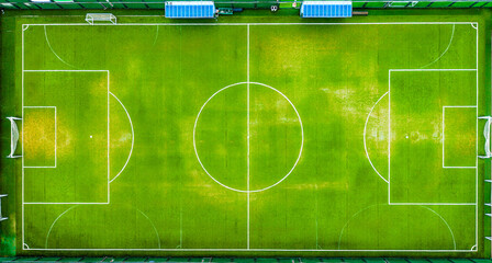 A perfect top-down aerial view of a vibrant green soccer field with white lines and goals,...