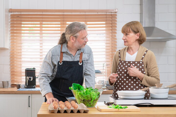Couple senior elder happy living in home kitchen. Grandmother cooking with grandfather with happiness and smile enjoy retirement life together. Older people relationship and activity.