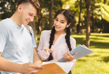 Happy diverse students studying with books, preparing for classes while walking in university...