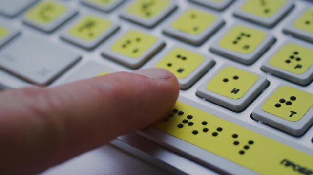Computer keyboard with braille font alphabet. Blind person is typing words, hands. Technological device for visually impaired people. Tactilely touches bumps on keys. Inclusion, assistive technology