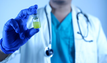 Close-up of a doctor or scientist's hand holding a vaccine vial. A vial of viral vaccine for injection is in the hand of a doctor or scientist technician. Concept of medicine and drugs.