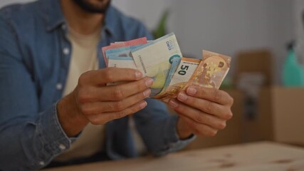 Man counting euro bills in a cozy living room interior, highlighting financial planning in a new home setting. - Powered by Adobe