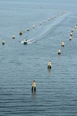 A lone boat navigates a marked channel in the Venetian Lagoon