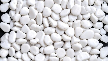 A close-up view showcases a collection of smooth, white pebbles. They are randomly scattered, creating a textured pattern against a dark surface