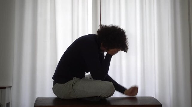 Desperate man in depression at home in bedroom despairs and cries for failure and panic attack and anxiety, loneliness and desperation lifestyle in  apartment after economic crisis  