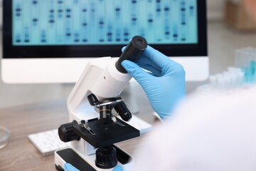 Research in genetics. Scientist working with microscope at table in laboratory, closeup